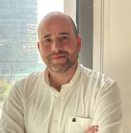 Persona con camisa blanca, fondo de edificio urbano.