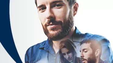 Hombre con barba y camisa azul con figuras superpuestas, fondo blanco.