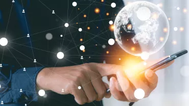 Persona usando un teléfono móvil con un holograma del mundo y conexiones de red.