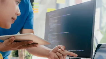 Personas colaborando frente a una pantalla con código.