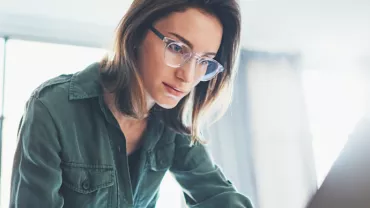 Persona con gafas trabaja concentrada frente a una computadora.