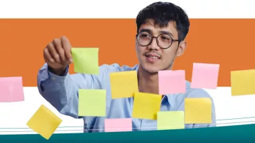 Persona organizando notas adhesivas en una pared.