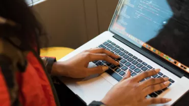 Persona escribiendo código en una computadora portátil.
