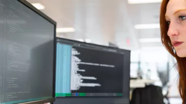 Persona trabajando en una computadora en una oficina moderna.