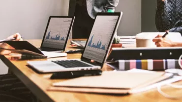 Reunión de trabajo con portátiles y gráficos en una mesa.