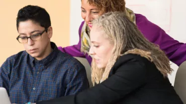 Tres personas colaborando frente a una computadora portátil.