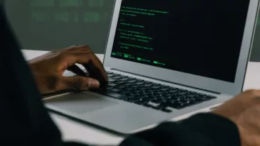Persona escribiendo código en una laptop.