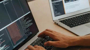 Persona escribiendo código en una computadora portátil en una mesa.