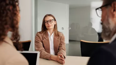 Reunión de negocios con tres personas sentadas alrededor de una mesa.