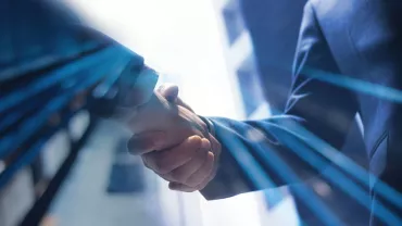Dos personas dándose la mano en un entorno profesional.