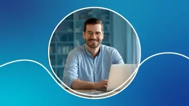 Persona sonriendo frente a una computadora portátil en casa.