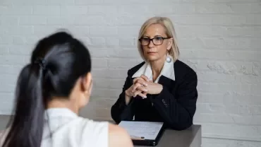 Profesional conversando con una consultora en una oficina moderna.