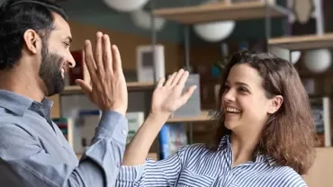 Hombre y mujer sonrientes chocando palmas