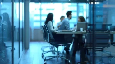 Equipo trabajando en un entorno empresarial, con un puesto vacío o silla libre que simbolice absentismo y rotación, reforzado por gráficos o dashboards de datos.