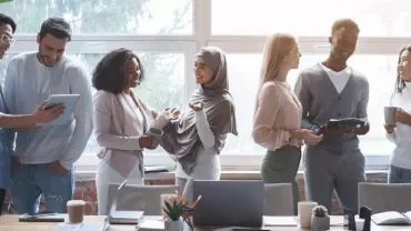 Equipo multigeneracional en entorno corporativo moderno colaborando en un espacio híbrido