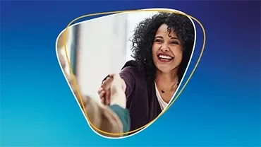 Mujer sonriendo mientras da la mano a otra persona frente a un fondo azul.