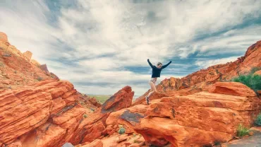 chica en la montaña con los brazos hacia el cielo