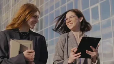 dos chicas saliendo de la oficina a una reunión con una tablet en las manos