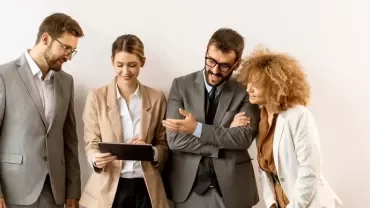 equipo de personas de oficina mirando una tablet y comentando entre ellos