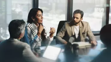 Dos profesionales reunidos en una entrevista de trabajo negociando una oferta laboral, revisando documentación y una propuesta salarial en un entorno de oficina moderno que transmite confianza, transparencia y profesionalidad. 