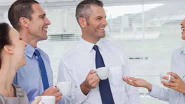 Grupo de personas conversando y bebiendo café en una oficina.