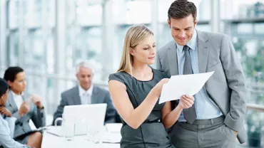 Personas trabajando en una oficina moderna, revisando documentos.