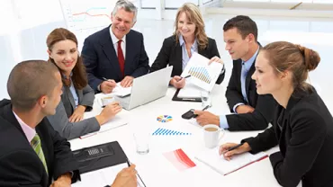Reunión de equipo en una mesa con gráficos y computadoras portátiles.