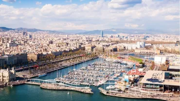 Vista aérea de un puerto lleno de barcos y una ciudad al fondo.