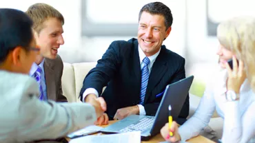 Personas en una reunión de negocios, sonrientes y estrechando manos.
