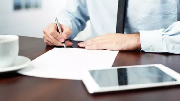 Persona firmando un documento en una oficina.