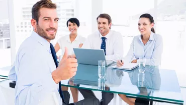 Un grupo de personas en una reunión de negocios, con una persona mostrando un pulgar arriba.