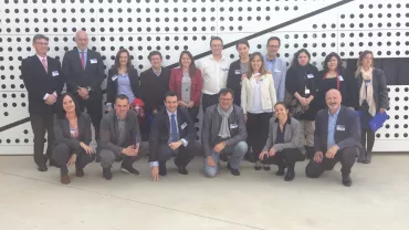 Grupo de personas posando frente a un fondo blanco con puntos negros.
