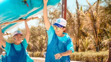 Personas llevando una balsa inflable azul en un día soleado.