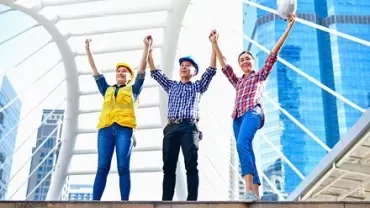 Trabajadores de la construcción levantan las manos juntos en una estructura moderna de la ciudad.