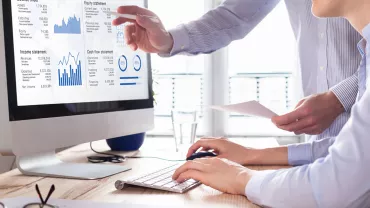 Personas analizando datos financieros en un monitor.