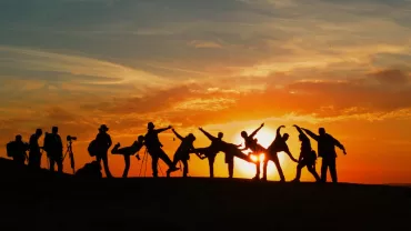 Personas en una colina al atardecer, capturadas en silueta.