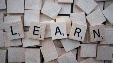 Letras que forman la palabra 'LEARN' en azulejos de madera.