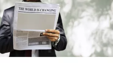 Persona leyendo un periódico con titular: El mundo está cambiando.