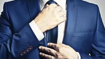 Persona ajustando una corbata azul.