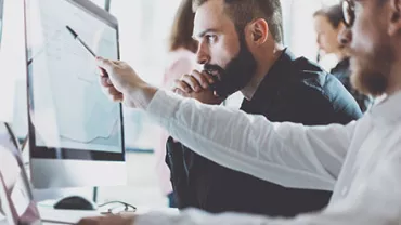 Personas trabajando en una computadora analizando datos.