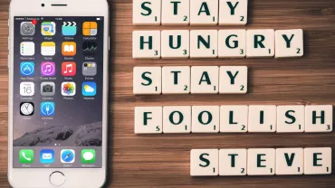 Teléfono junto a letras que forman la frase 'Stay hungry, stay foolish, Steve'.