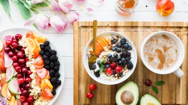 Mesa con frutas, yogurt, café y flores.