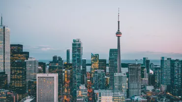Skyline urbano al atardecer con torre alta y edificios modernos.