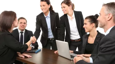 Grupo de personas en una reunión empresarial con traje formal.