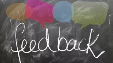 La palabra 'feedback' escrita en un pizarrón con bocadillos de colores.