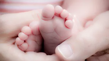 Pies pequeños de bebé sostenidos por manos adultas.