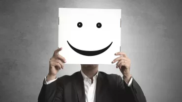 Persona sosteniendo un cartel con una cara sonriente.