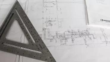 Planos de tuberías con una escuadra de medición encima.