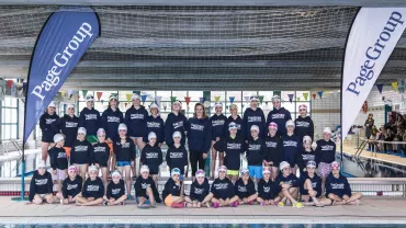 Grupo de personas en una piscina cubierta con camisetas a juego.