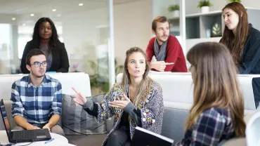 Personas conversando en una reunión en una oficina moderna.